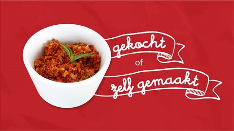 Een wit potje tapenade op rode achtergrond met tekst: "gekocht of zelfgemaakt"